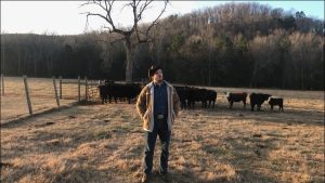 Willi Carlisle stands in front of some cattle in Mount Olive, Arkansas