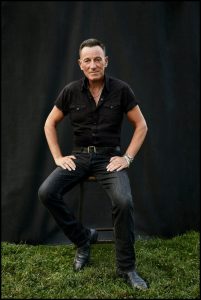 Bruce Springsteen seated on a stool