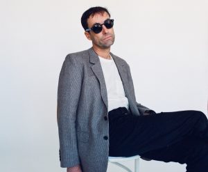 Andrew Bird seated, with sunglasses